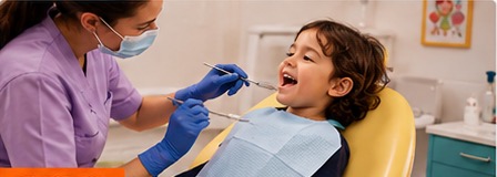 Dentist examining a smiling child's teeth.